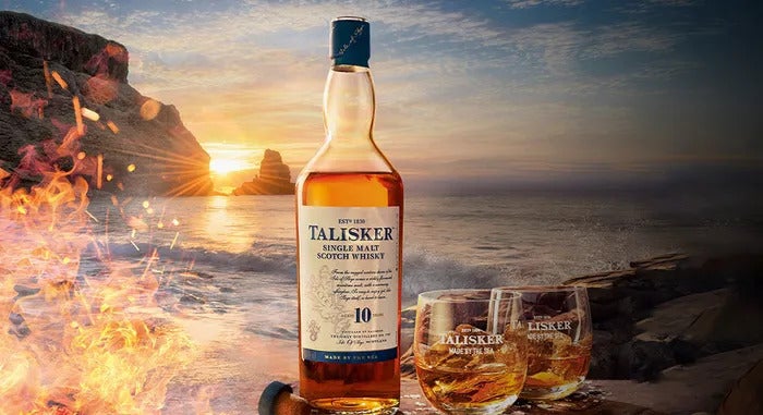 Bottle of Talisker 10 year single malt next to tumbler glass of whisky by the ocean