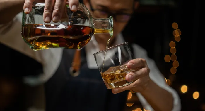 Man pouring whiskey from a fancy bottle into a glass