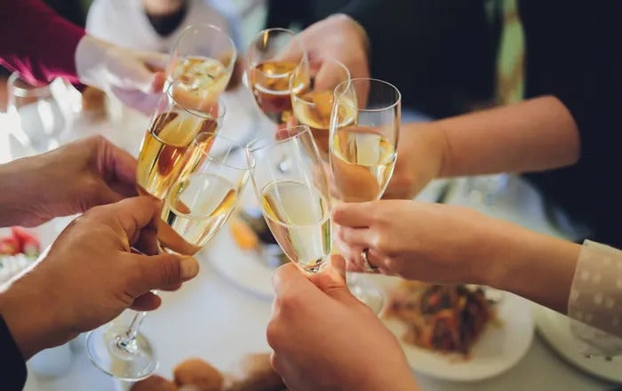 7 glasses of Champagne being clinked together during a toast at a fancy event