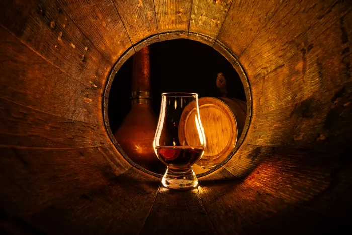 Whisky glass in an empty wooden barrel