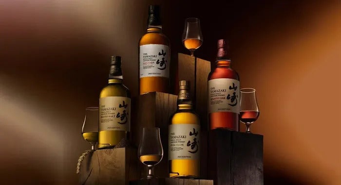 Different bottles of Yamazaki whisky next to whisky glasses displaying the differences in colours and flavours